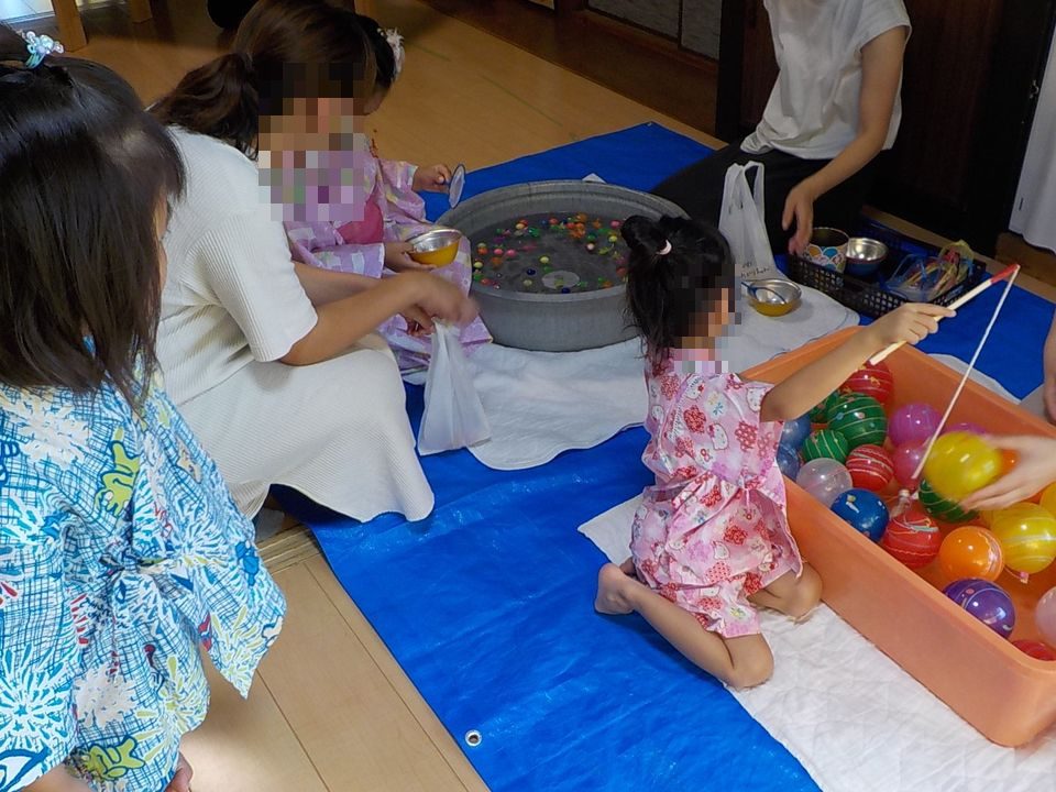 夏祭りの水風船あそびを親子で楽しむ様子